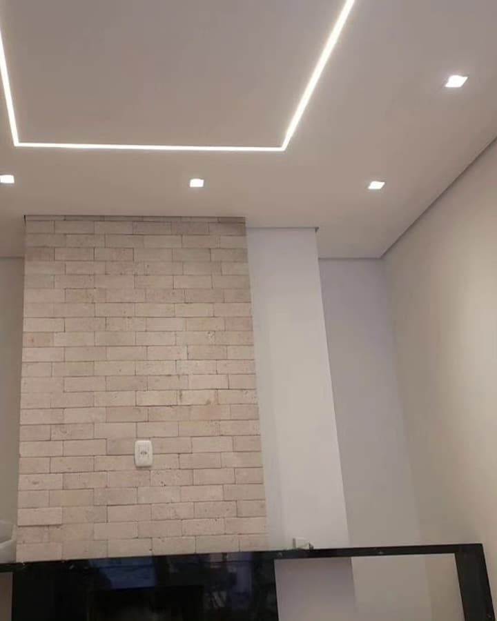Parede revestida em pedra com sanca iluminada no teto